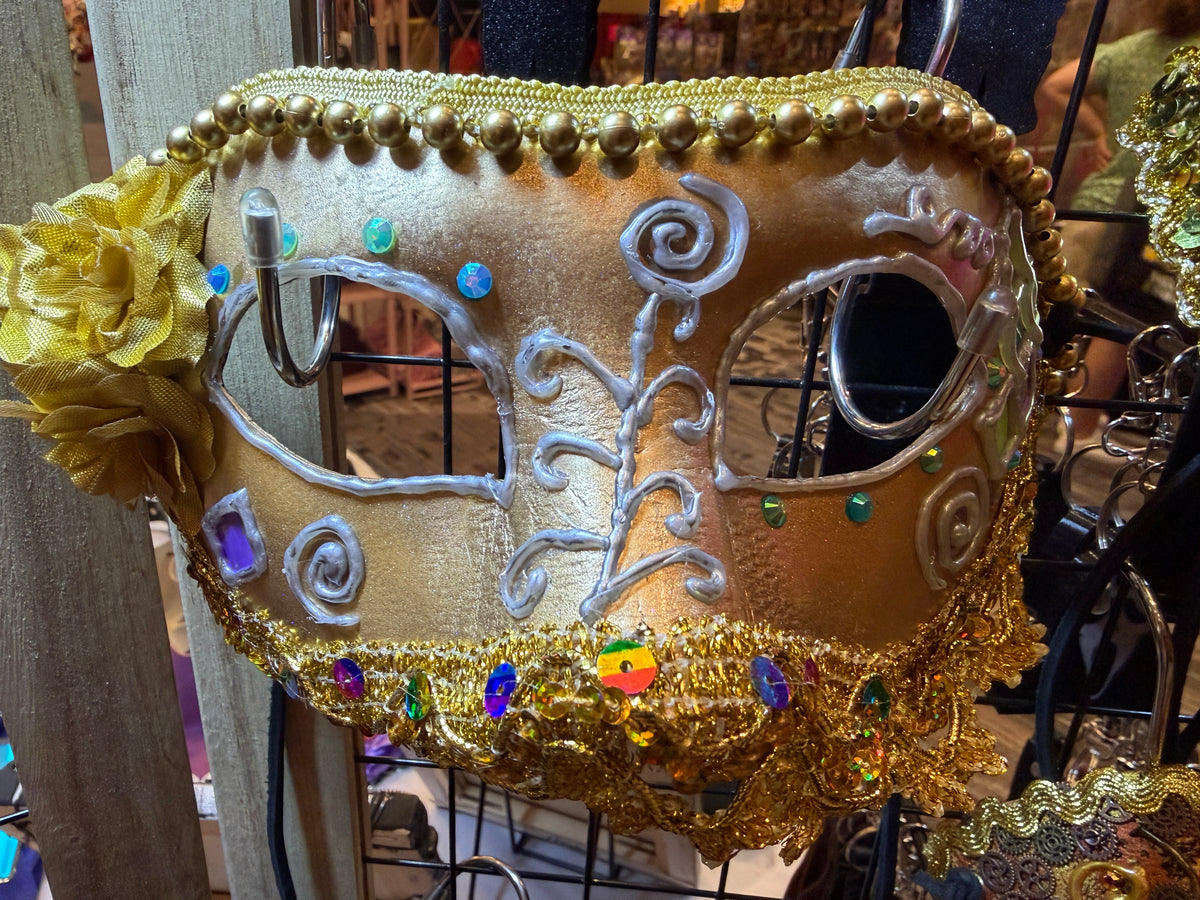 Decorative mask with gold and silver design, featuring flowers and beads.